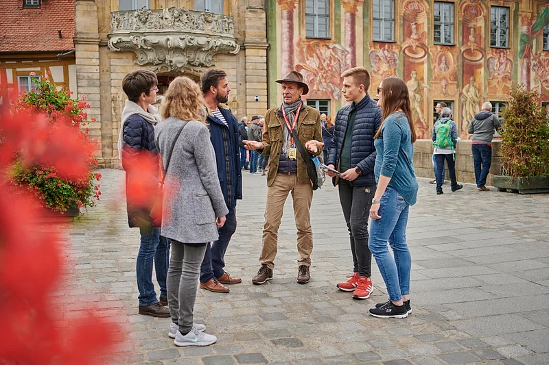 BAMBERGcard Stadtführung Eine Stadtführungs-Gruppe steht vor dem Alten Rathaus in Bamberg.